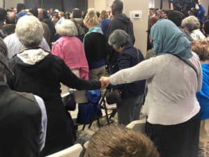 Women holding hands with heads bowed