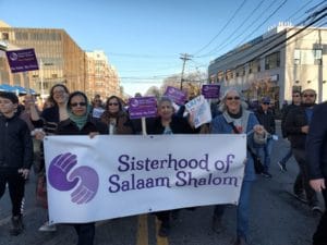 Women gathered by Sisterhood banner at outside event