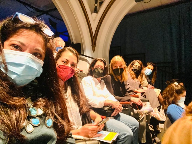 Seated women in a theater wearing masks