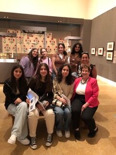 Seven teens and two adults on a bench in the Collection of Islamic Art exhibit