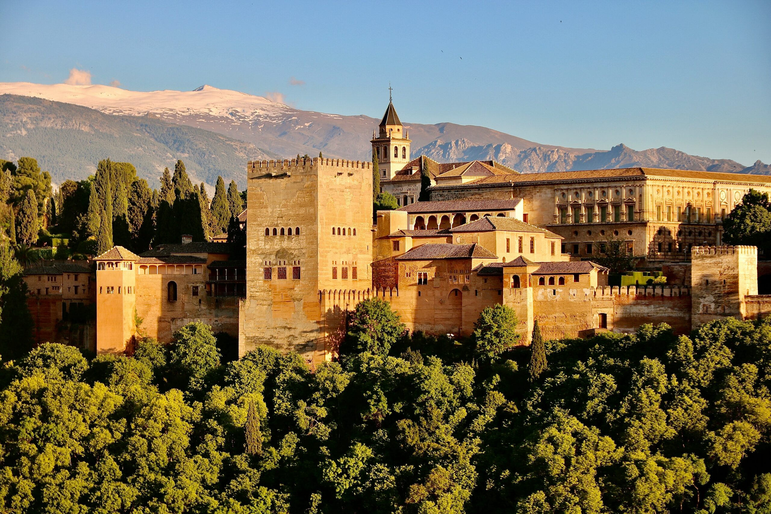 picture of the alhambra set in the trees against a clear blue sky