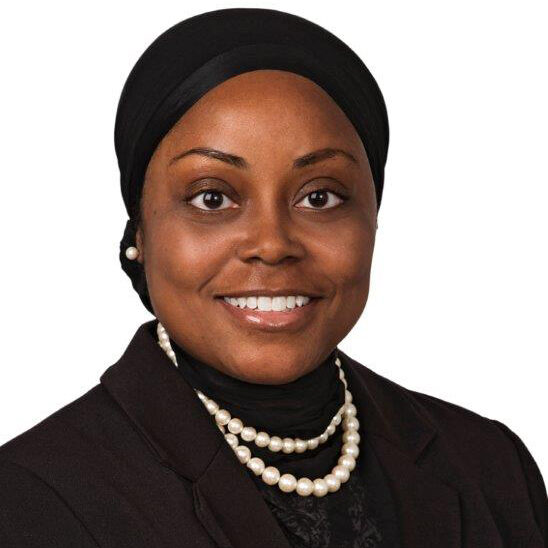 photo of black woman in headscarf with double strand pearl necklace and black blouse
